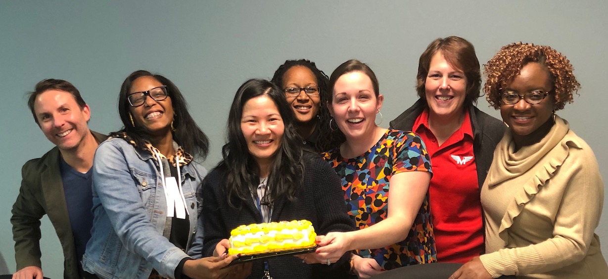 Thanh-Thuy T. Nguyen, holding a cake, is surrounded by her classmates celebrating the day she defended her dissertation to receive her doctorate