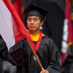 international student carrying a flag of his country at graduation