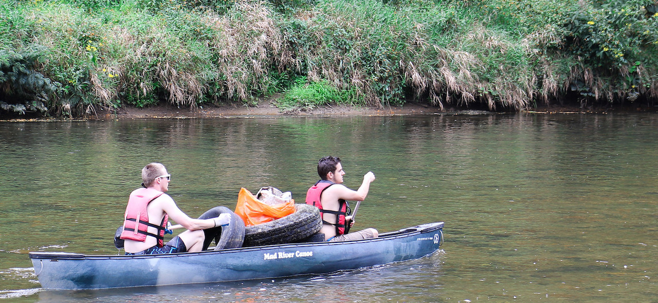 Two students paddling a canoe down the river