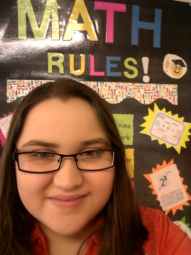 Chasity McCraw in front of math rules poster in her classroom