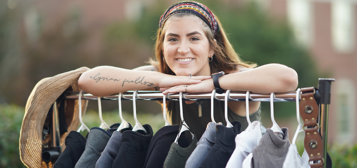 Carlee Winstead poses with a rack of clothes.s of fast fashion.