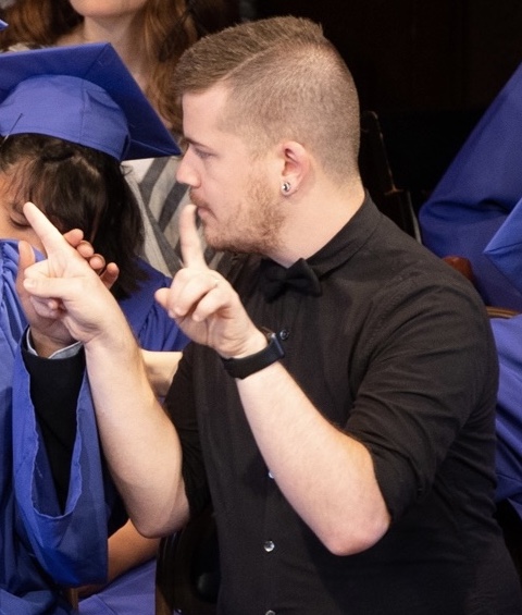 Jon Urquhart interprets for a person at a graduation ceremony.