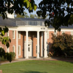 The front of Webb Hall, which is surrounded by trees and shrubs