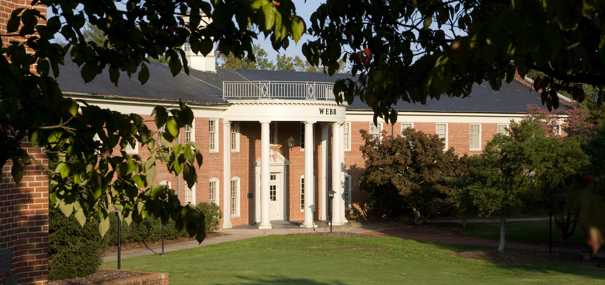 The front of Webb Hall, which is surrounded by trees and shrubs