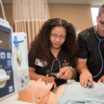 two nursing students with practice mannequin