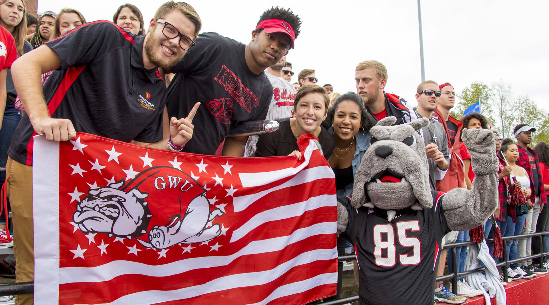 GWU students with mascot at homecoming game holding GWU flag