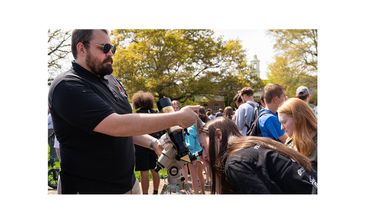 GWU Professor Wilson with student looking through telescope on campus