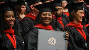 A graduate smile as she displays her diploma