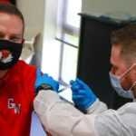 Dr. William Downs, GWU President, gets a COVID-19 Vaccine from a healthcare worker.
