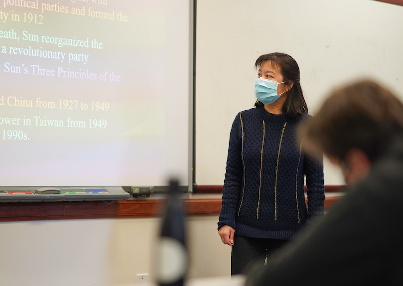 Dr. Aihua Zhang stands at the whiteboard in her class.