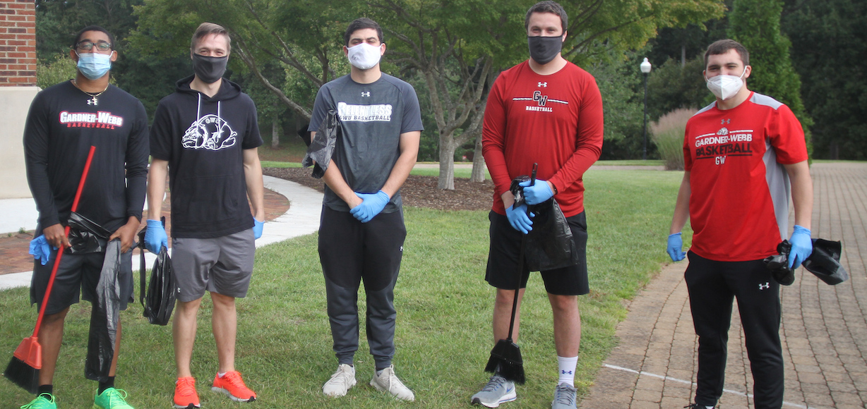 a photo of five male students holding cleaning supplies ready to participate in a day of service