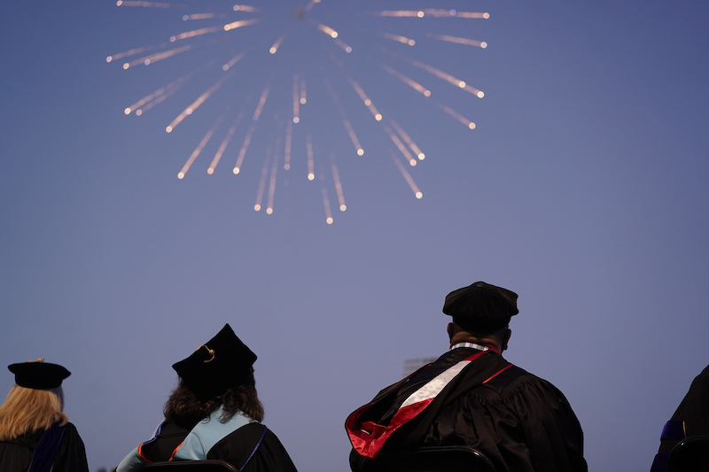Fireworks light the sky over the heads of graduates