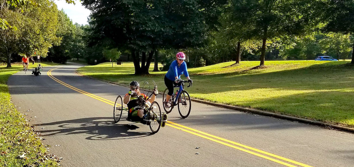 Jacob Conley rides a handcycle and Dr. Shea Stuart rides a bicycle at Cowpens Battleground.