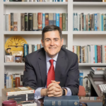 russell moore sitting at a desk in front of shelves of books