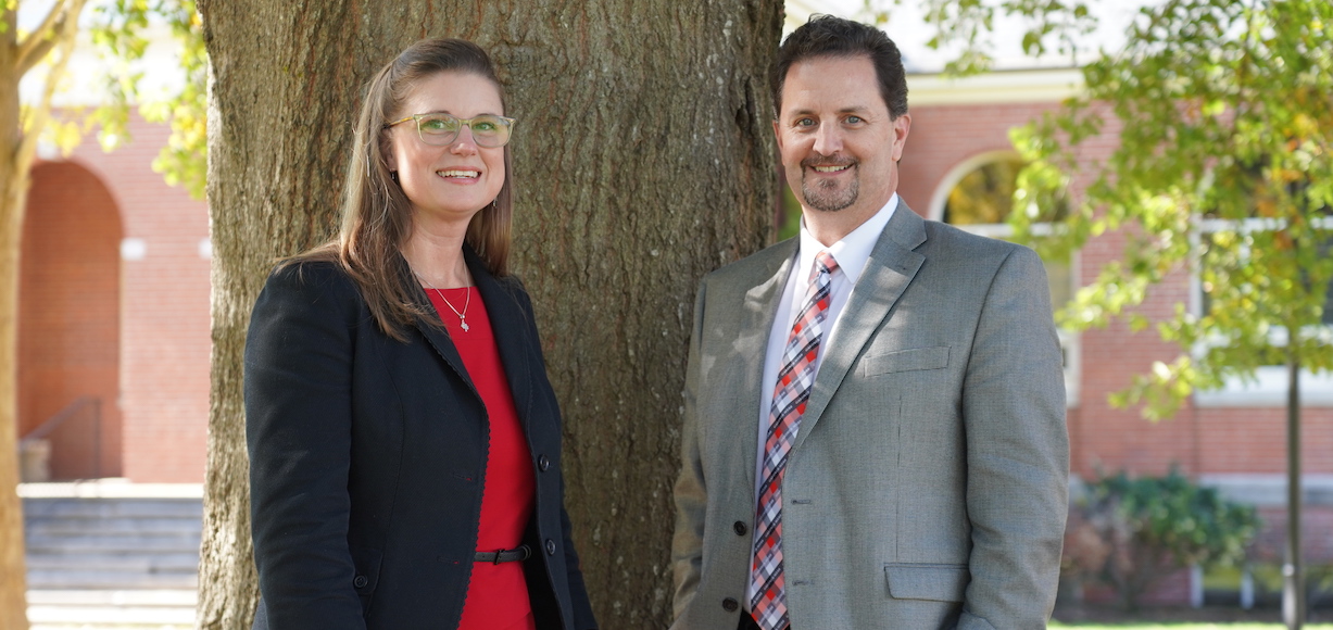 Associate Dean Jennifer Buckner and Dean Shawn Holt pose in front of a tree on the GWU Campus