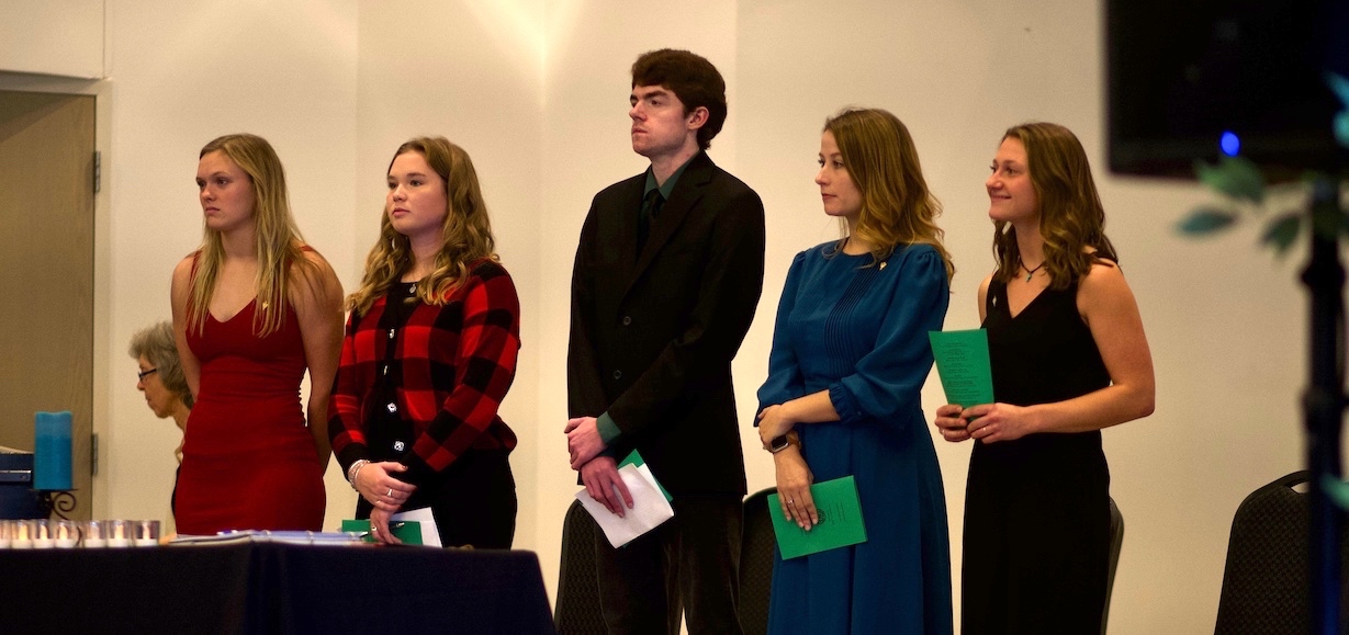 The five officers of Alpha Sigma Chi stand on stage during the induction ceremony