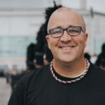Matt Harloff stands in front of a marching band.