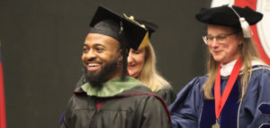 A student receives a hood during graduation.