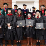 A group of divinity school graduates and professors pose after graduation in December 2021