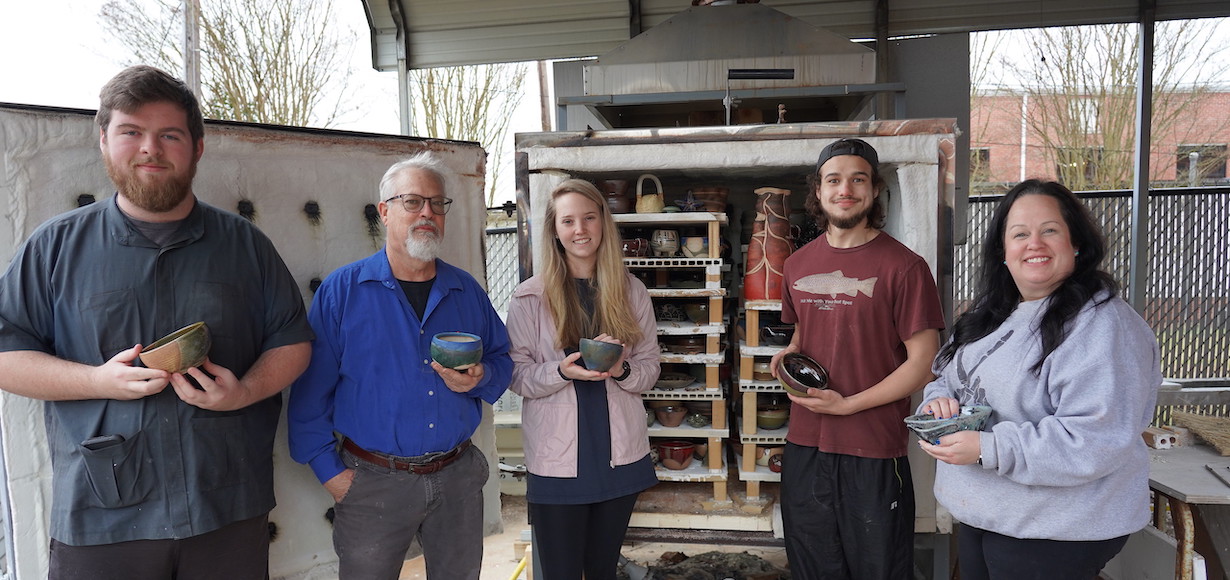 The students and Doug Knotts pose with their bowls that have just come out of the kiln.