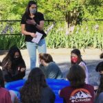 Sarah Laurence, standing, leads a group of young people in an activity.