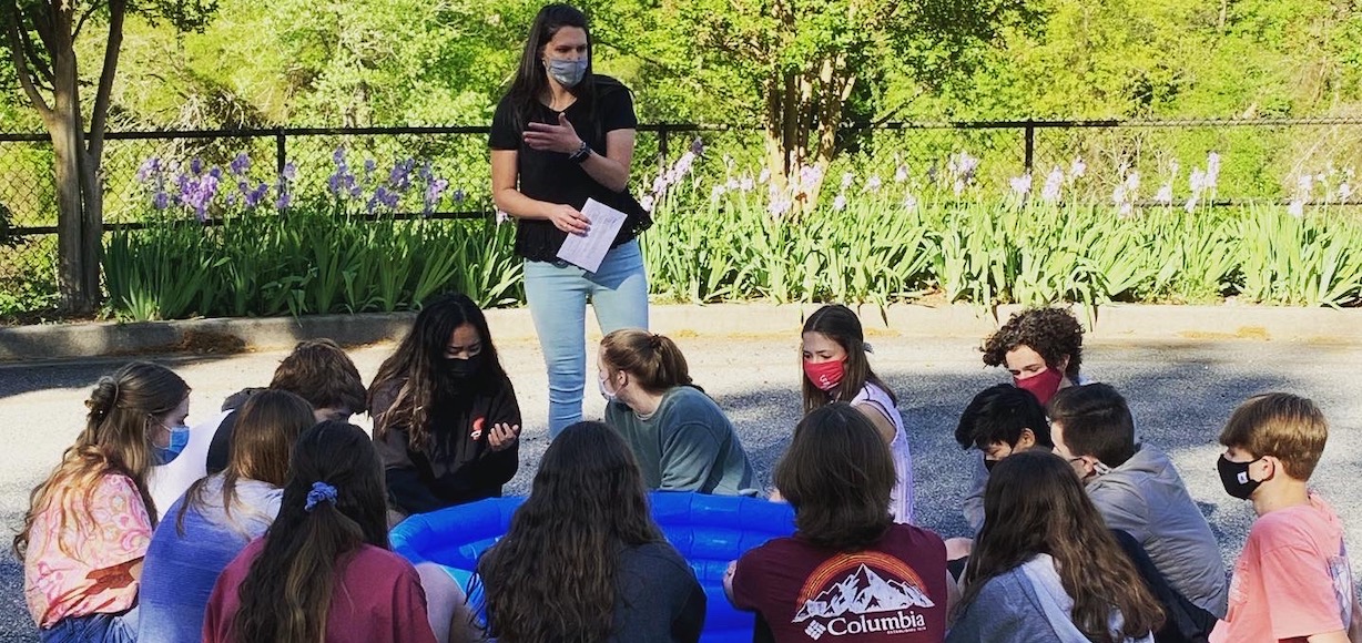 Sarah Laurence, standing, leads a group of young people in an activity.