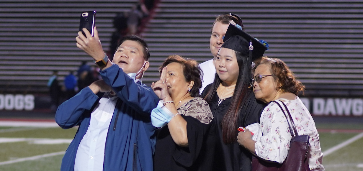 a family poses for a selfie after graduation in May 2021.