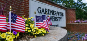 Small American flags are placed in front of a Gardner-Webb sign