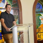 Neal Payne standing in front of the stained glass in Tucker Chapel