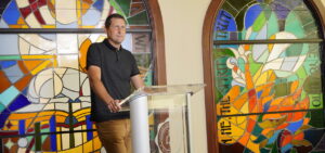 Neal Payne standing in front of the stained glass in Tucker Chapel