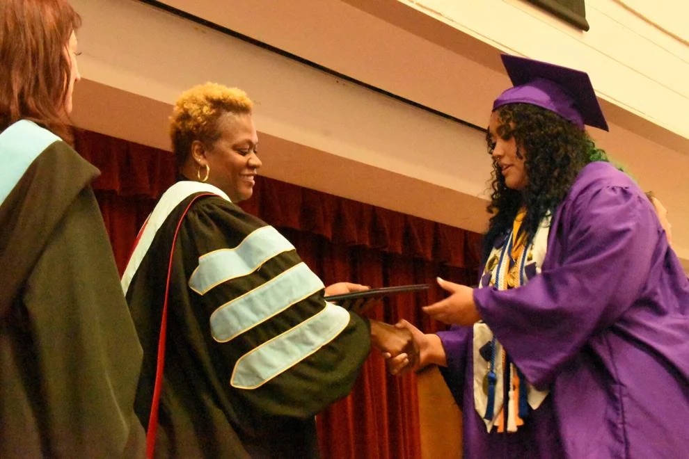 Nicole Ijames presents a diploma to a student at graduation