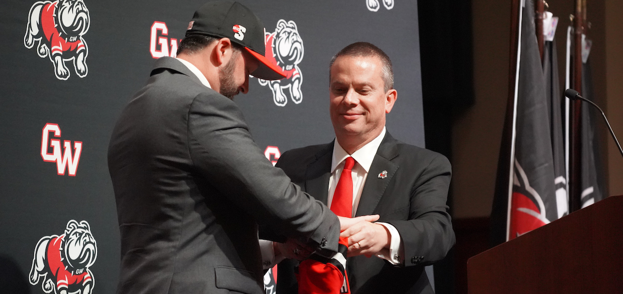 Dr. Downs right presents new VP and Director of Athletics Andrew Goodrich with GWU Swag