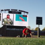 A photo of Jerry Gass is on the scoreboard with CrossFit competitors in the foreground