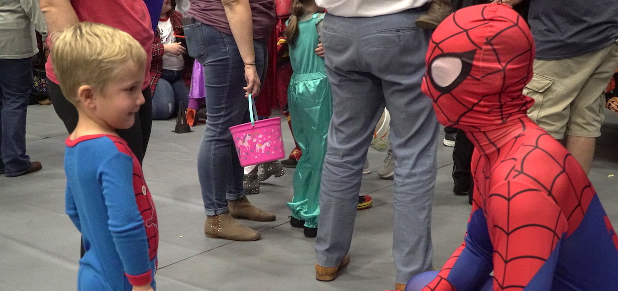 A youngster in a Spiderman costume sees an older person in a Spidey costume.P