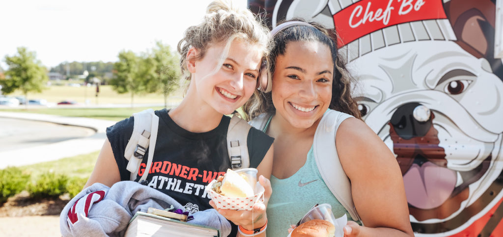 Two girls hold sandwiches from the food truck