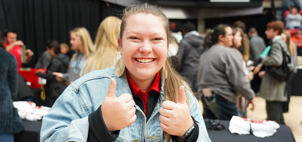a girl smiling and giving a thumbs up
