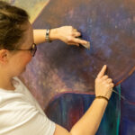 Natalie Bishop works to remove the mural from the wall