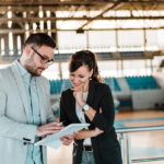 Two adults talking over a notebook in a sports hall