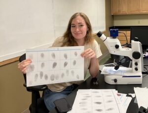 a student holds up a paper with fingerprints on it