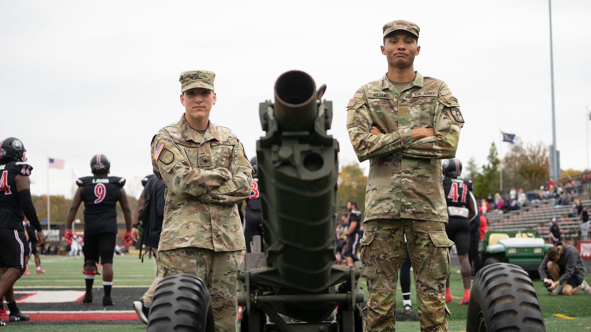 male and female ROTC soliders with cannon at GWU football game
