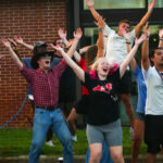a group of students dancing in the parking lot during the welcome celebration