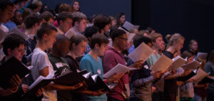 several choir students sing in a practice at Dover Theatre