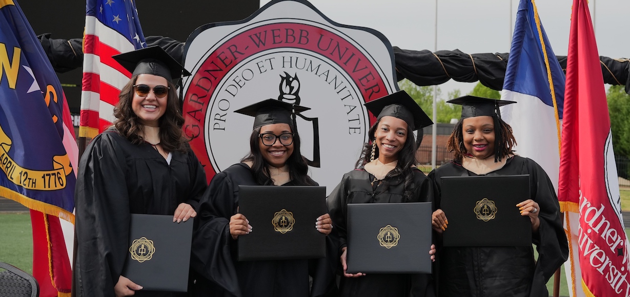 Four female graduates pose after the ceremony with their diplomas