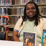 Brandon Richmond poses with his books in the library