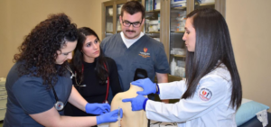 Ashley Kernicky, right, instructs three students on giving shoulder injections.