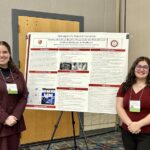 Four students standing next to their poster presentation