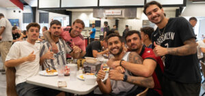 A group of soccer players eating in the cafeteria