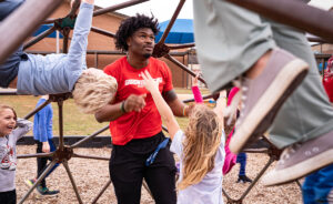 GW football player plays with children on playground