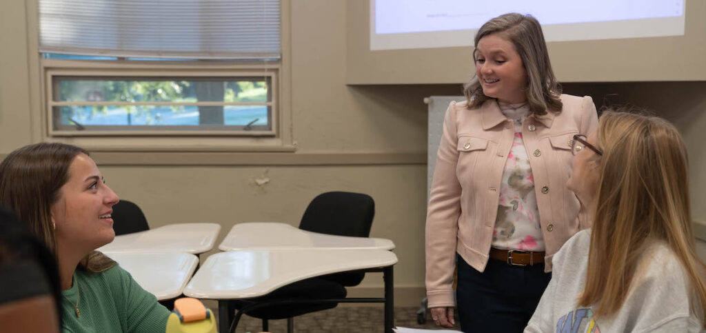 Brittany Evans talks with a couple of students in class