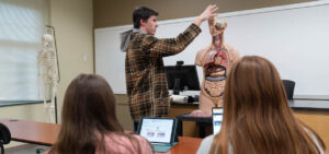 Benjamin Rogers in the anatomy lab with a couple of students and a mannequin